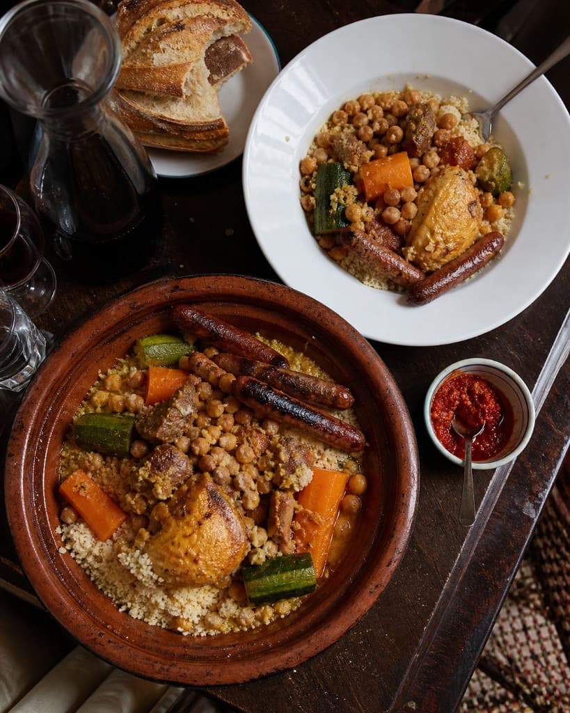 Couscous royal généreux dans un grand bol blanc avec merguez, agneau et légumes